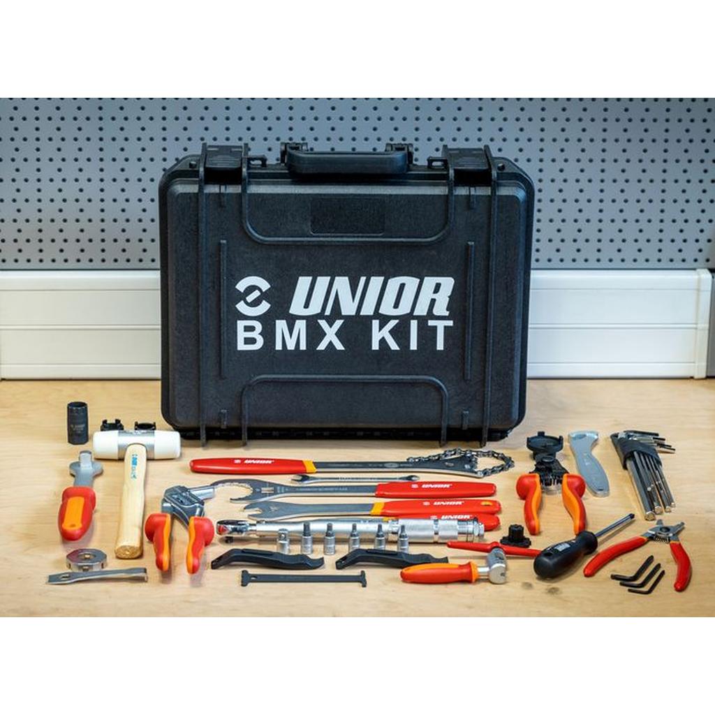 The Unior Hardcase Tool Set includes 43 tools for BMX bikes such as wrenches, pliers, a hammer, screwdrivers, and a chain tool, all organized in a hard case and displayed on a workbench.