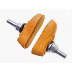 The Kool Stop X Vans Brake Pads are shoe-shaped bicycle brake pads with vibrant orange soles and metal attachments, utilizing rim-friendly compounds for efficient stopping.