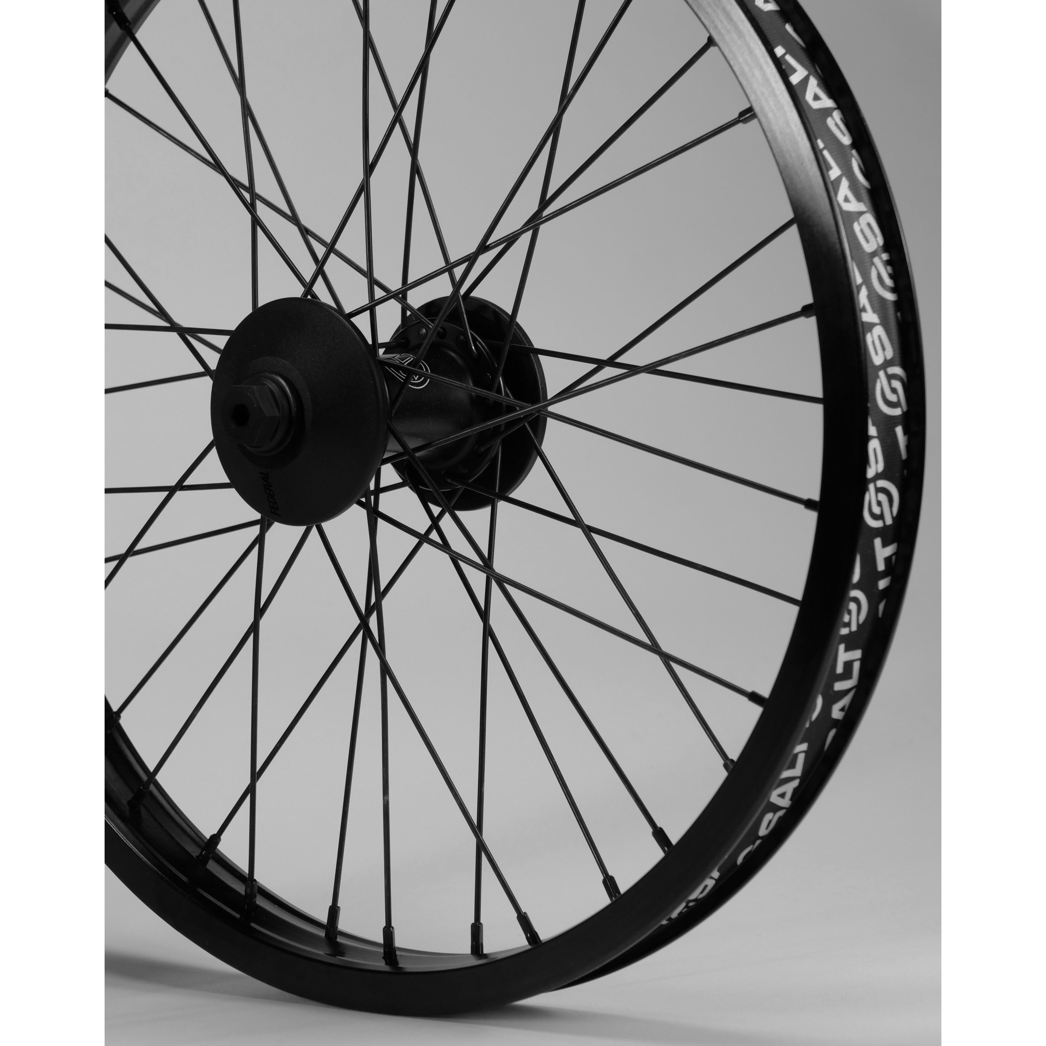 Close-up of a bicycle wheel with spokes, showing detailed view of the Federal Stance Pro x Alienation 18 Custom Wheelset hubset and rim against a neutral background.