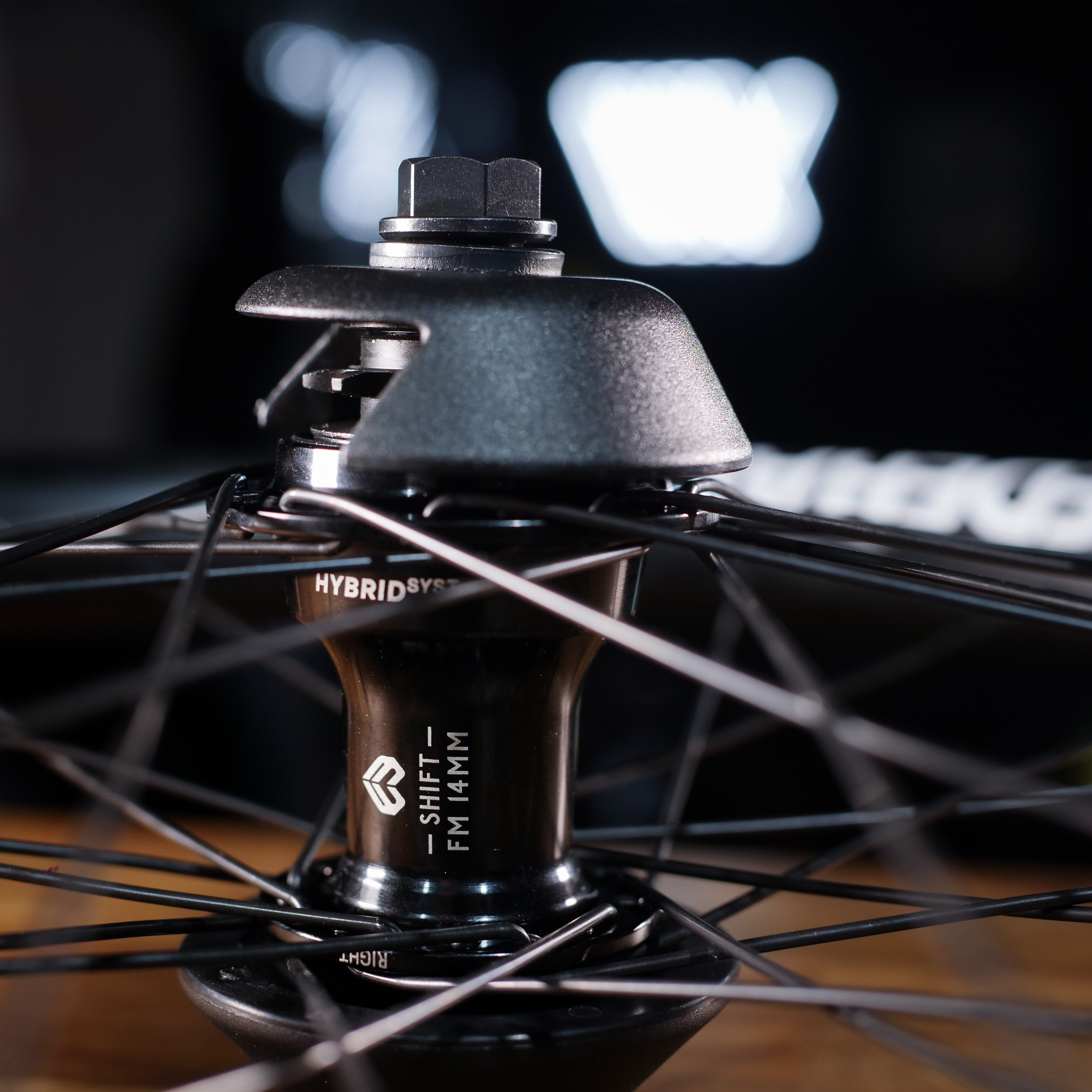 Close-up of the Federal X Eclat FM Shift Hybrid Custom Wheel shows a hub labeled "HYBRID SYSTEM" and "SHIFT FM 141M," with spokes radiating outward against a blurred background.