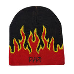 The Cult Flame Beanie is a black acrylic skull cap with a striking red and yellow flame design and an embroidered "CULT" logo on the front.