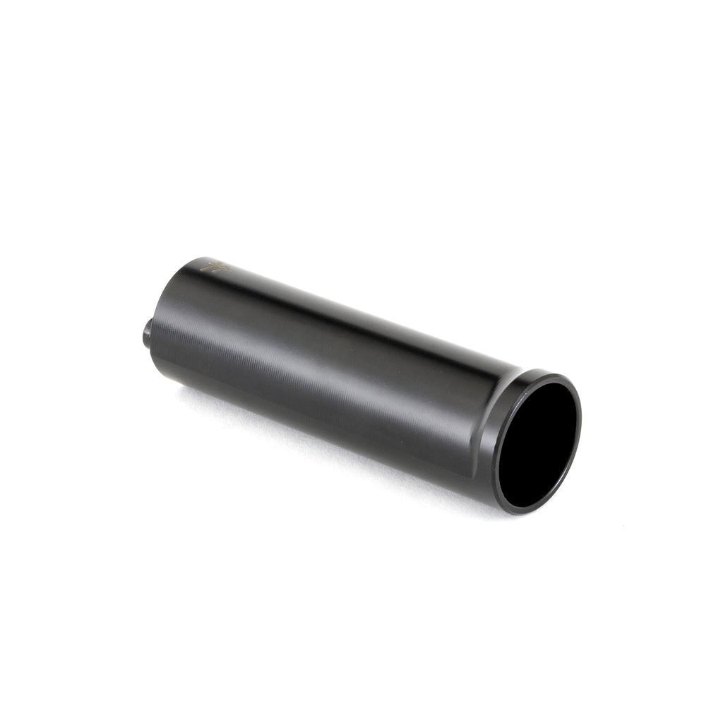A black Fly Bikes Acero TR Peg (Each), a cylindrical tube with one open end, rests on a white surface, viewed from a slightly elevated angle.