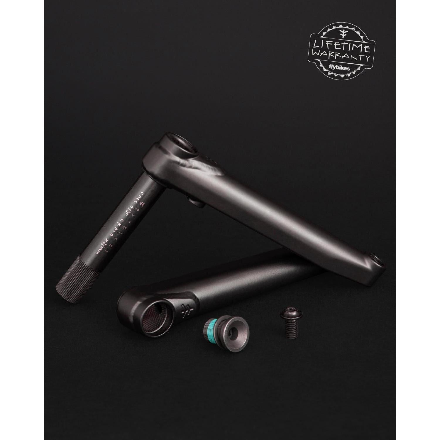 Bicycle crankset parts on a black background, featuring two black Fly Bikes Dolmen 24 Cranks made of 4130 Chromoly, accompanied by a bolt and nut. A "Lifetime Warranty" label is prominently displayed in the top right corner.