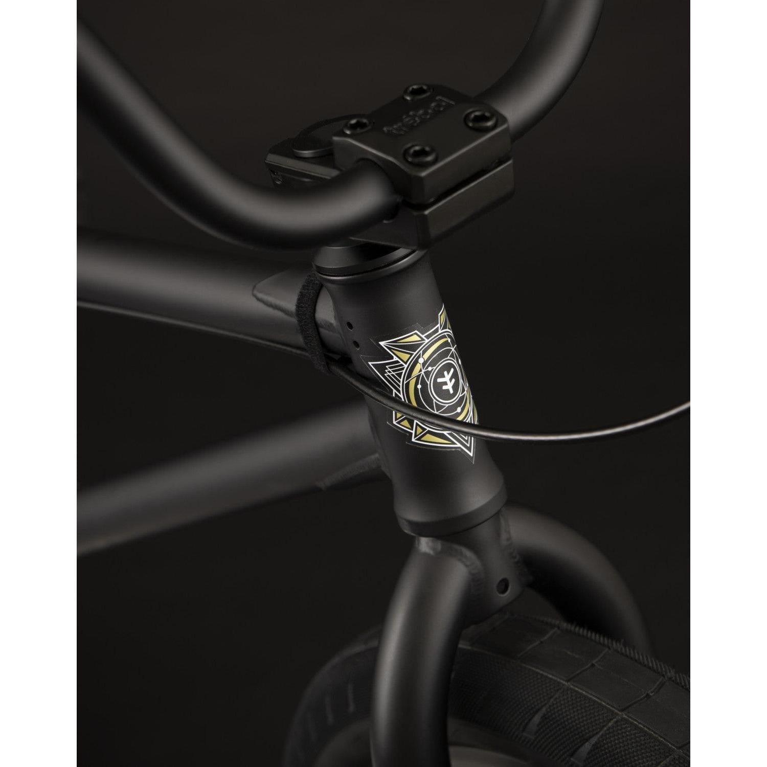 Close-up of a Fly Bikes Electron 20 Inch Bike's black matte handlebar and frame, showcasing a geometric emblem and intricate cable detailing, all crafted with Cr-Mo material for durability.