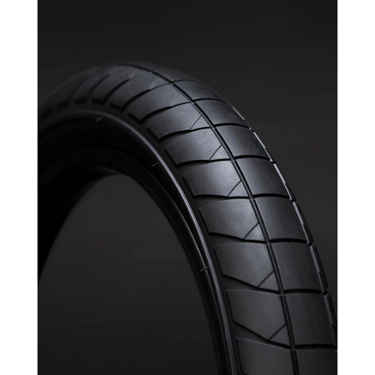 Close-up of the Fly Bikes Fuego 18 Inch Tyre STD, showcasing its distinct tread pattern and enhanced performance with HPPR layer technology, set against a dark background.