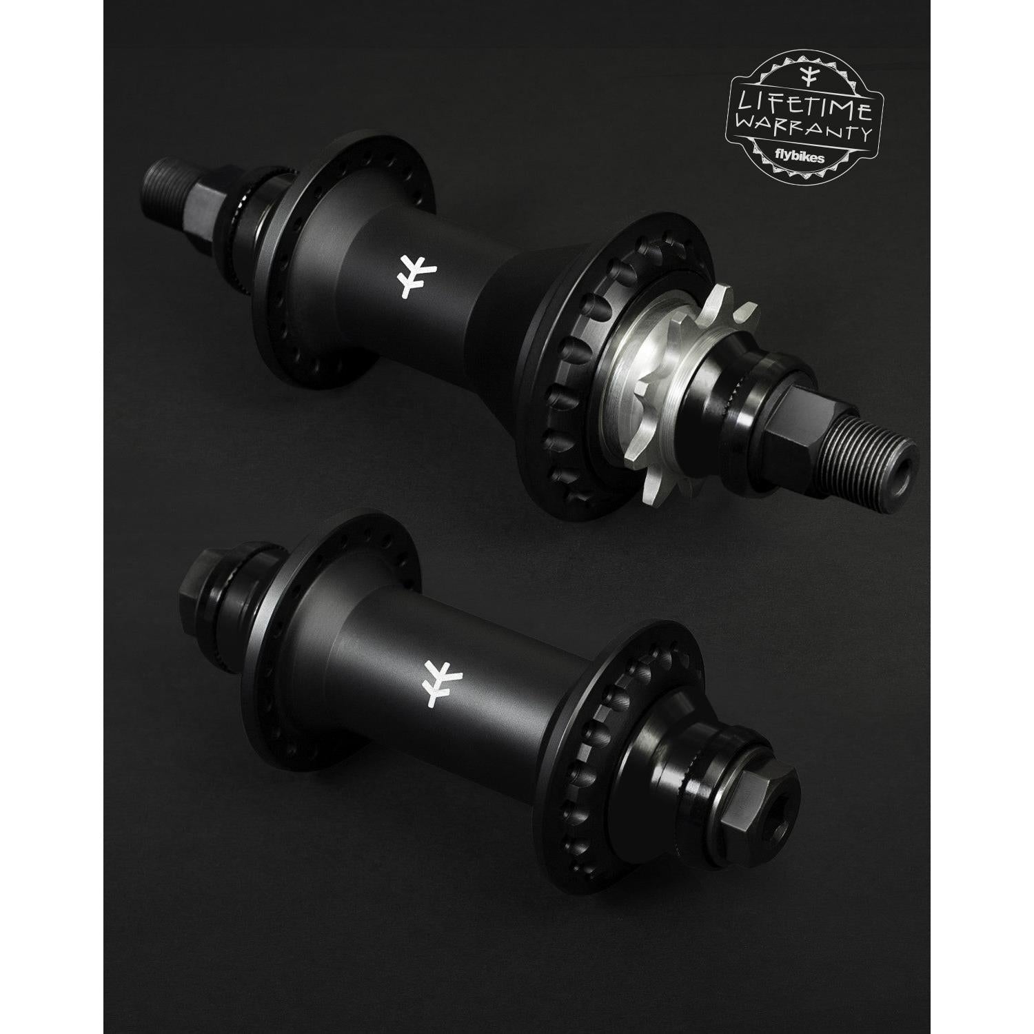 Two black Fly Bikes Magneto Hub Set (Crmo) bicycle hubs on a dark background, one showcasing a cassette with cog and chainring. "Lifetime Warranty" logo in the upper right corner.