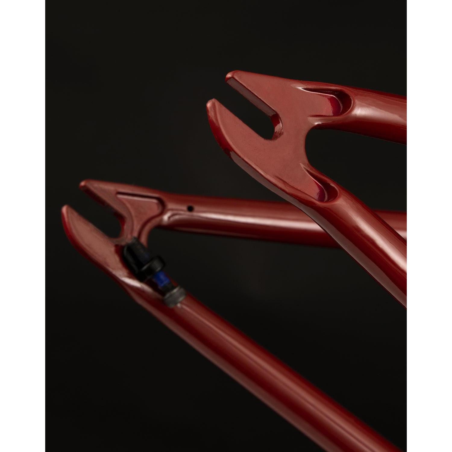 Close-up of the Fly Bikes Motosierra Frame in red, showcasing its fork ends against a black background, with precision-welded chainstay brake mounts.