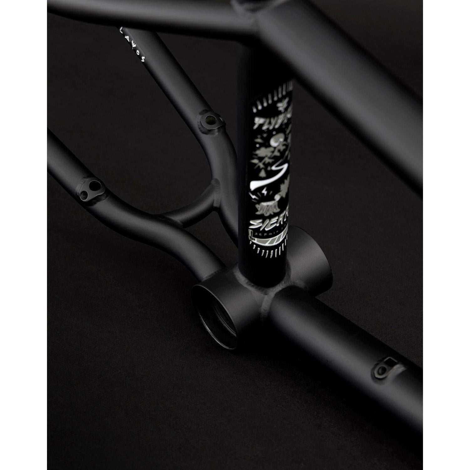 Close-up of a matte black Fly Bikes Sierra 18" BMX frame with branding details, showcasing the Sergio Layos signature design against a dark background.