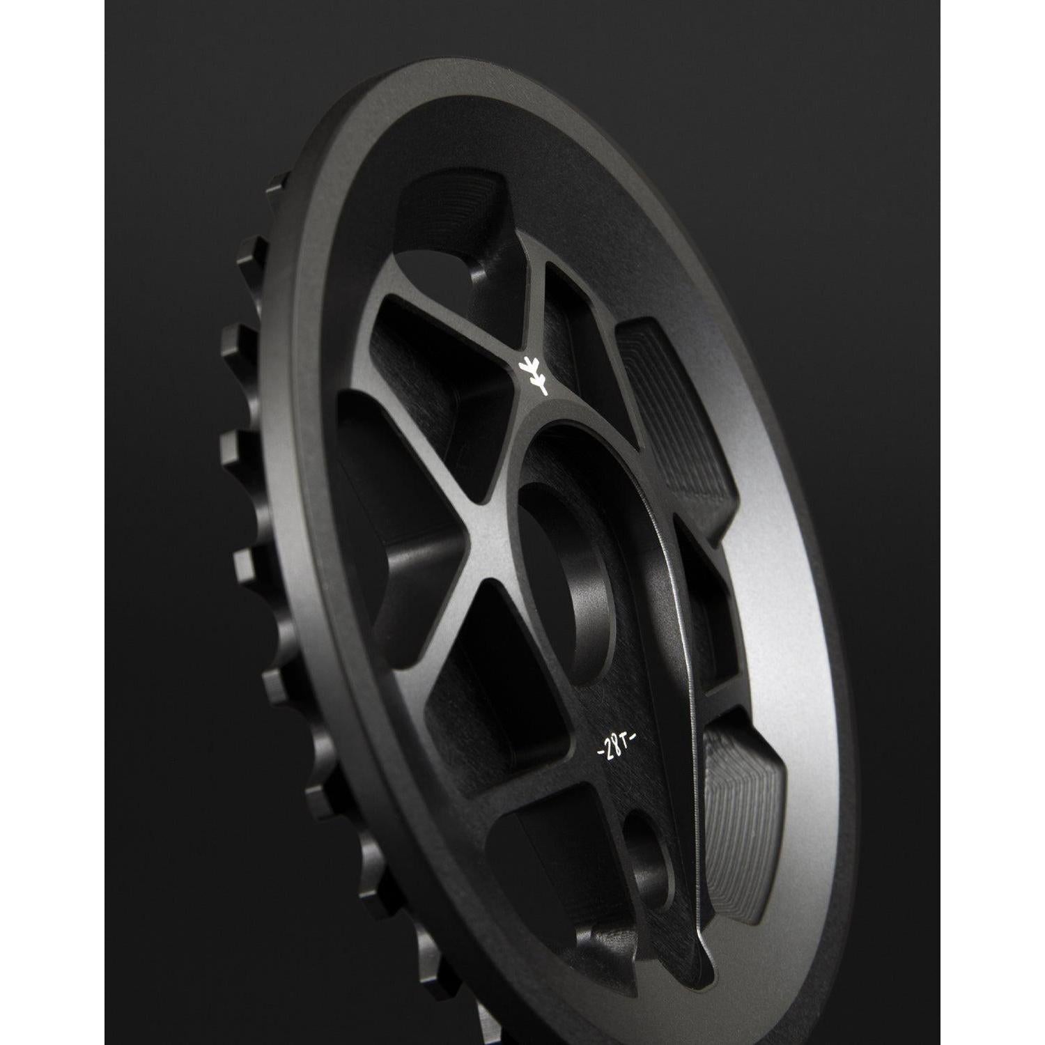 Close-up of the Fly Bikes Tractor Guard Sprocket, precision CNC machined from 6061 Aluminum, highlighting its intricate grooves and teeth against a dark background.