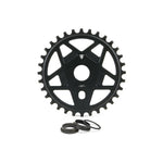 The Fly Bikes Tractor TT Sprocket is a sleek black gear made of 6061 T-6 Aluminum, designed with a central hole and edge teeth, accompanied by three circular washers for display.