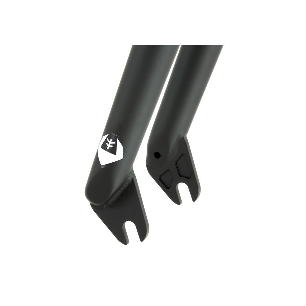 Close-up of a black Fly Bikes Volcano Fork dropout, showcasing a logo and slots for attaching the wheel axle. The design ensures optimal tire clearance and effortlessly accommodates BMX steer-tubes.