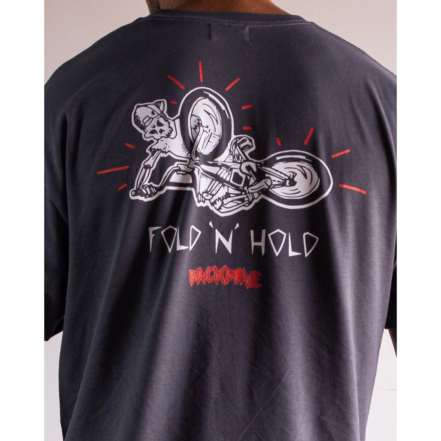 Someone wearing the Backbone Fold 'N' Hold t-Shirt, made of premium cotton, featuring a dog on a motorcycle with "FOLD 'N' HOLD" and "BACKDAME" on the back—ideal for Backbone BMX fans.