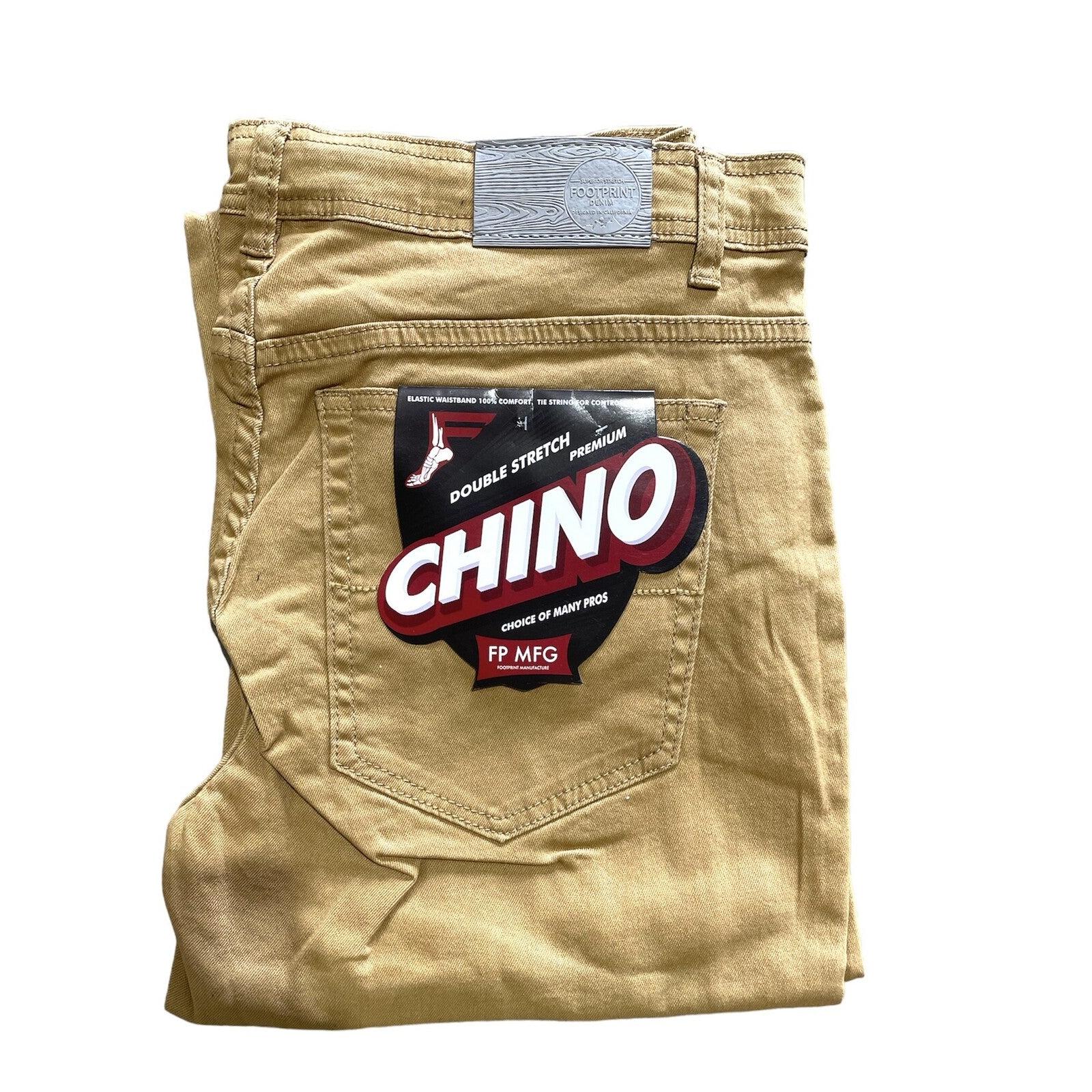 Folded pair of beige chino pants with a label on the back pocket that reads "FP Pants Relaxed Fit Chino Tan" and "FP MFG." These relaxed fitting chino pants offer both comfort and style.