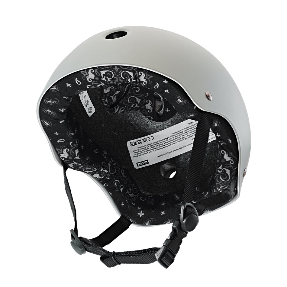 Gray Goodstock Certified Helmet / Matte Gunmetal/Bandana with an intricate black and white interior design and a chin strap, featuring a label with specifications. This certified skate/bike helmet offers high and low impact protection, along with CoolMax liner tech for added comfort.