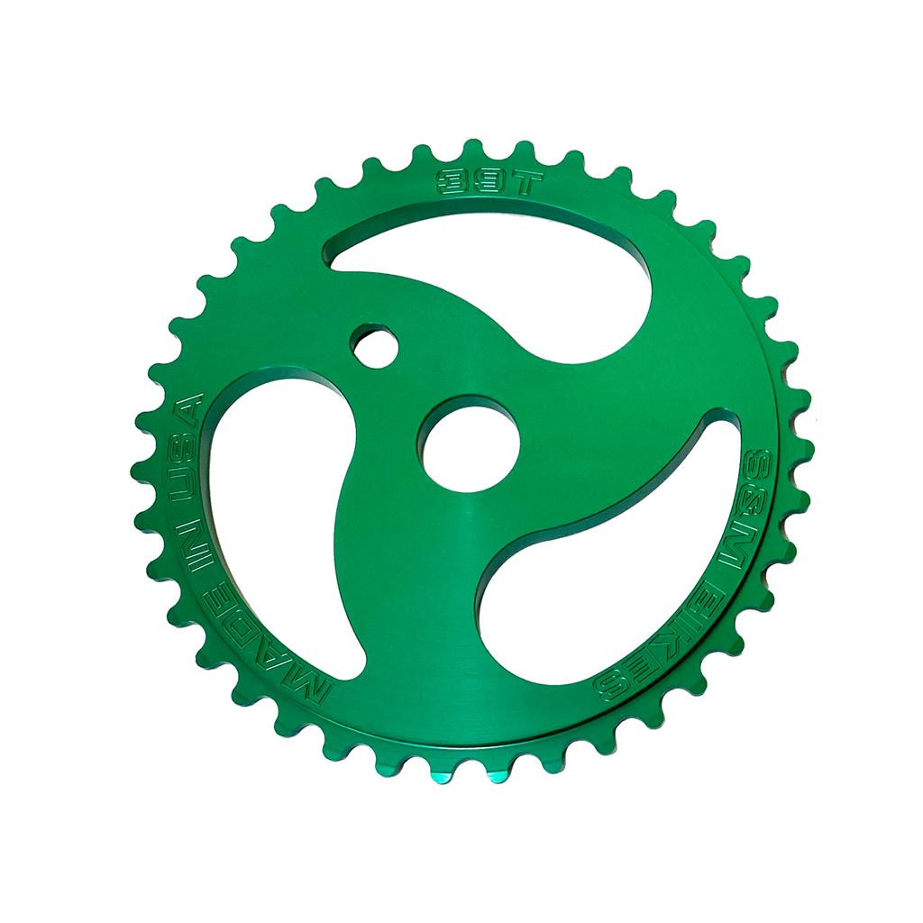 The S&M Chainsaw Sprocket is a green CNC-machined metal bicycle sprocket with 38 teeth, three cutouts, and markings: "38T," "MADE IN USA," and "S&M BIKES.