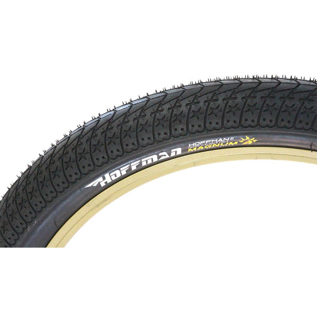 Close-up of a black Hoffman Bikes Magnum Tyre with textured tread and "Hoffman Magnum" in white/yellow on the sidewall. Size: 20 x 2.35, designed for BMX bikes.