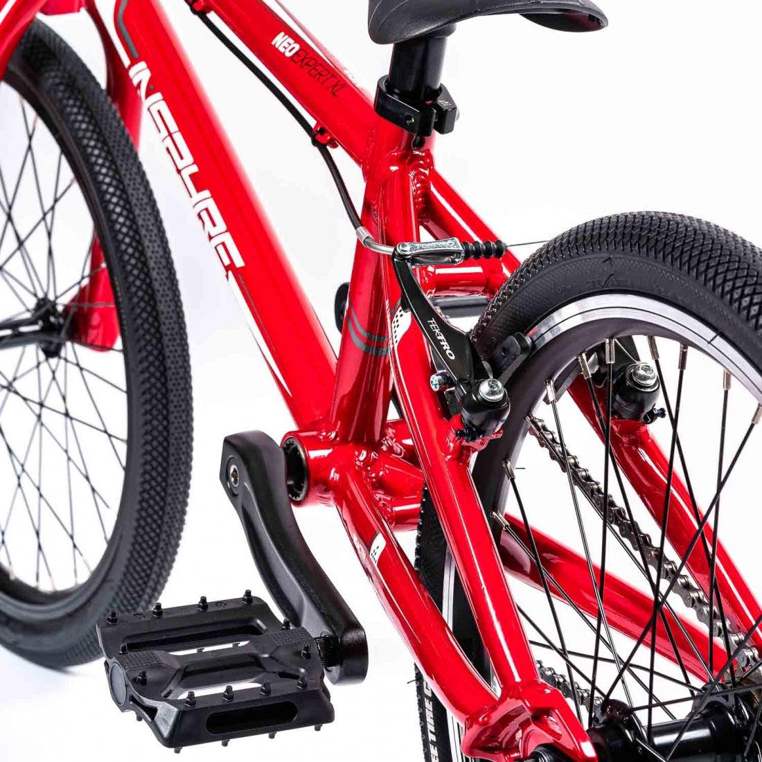 Close-up of a red Inspyre Neo Junior Bike showcasing its frame, pedals, and rear tire.