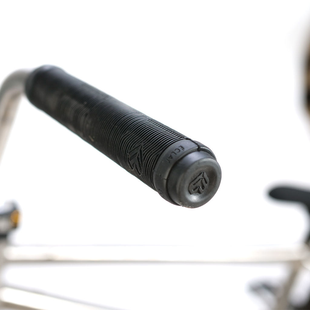 Close-up of a textured handlebar grip with a branded end cap on an ION BMX TiXX 20 Inch Bike titanium frame.