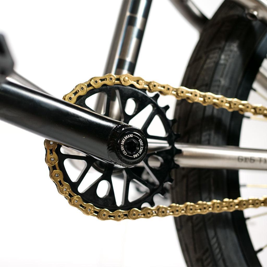Close-up of an ION BMX TiXX 20 Inch Bike drivetrain showing a gold chain on a black sprocket.