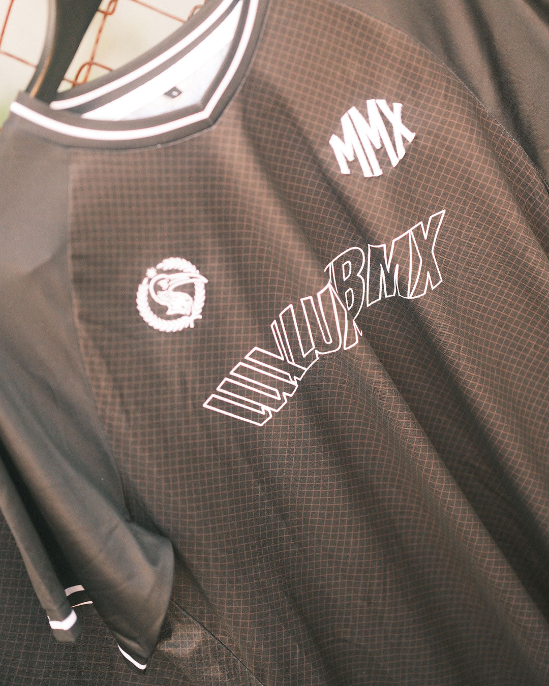 The LUXBMX MMX Soccer Jersey - Custom Back Print is a black and gray breathable jersey featuring white “MMX” and “LUXLUBMX” text on the front with a circular dragon logo—perfect for your next LUXBMX ride.