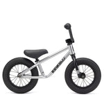 The Kink Coast 12 Inch Balance Bike features a minimalist silver frame with black saddle, grips, and tires. Designed like a pedal-free kids BMX, it's perfect for young children to improve balance while riding.