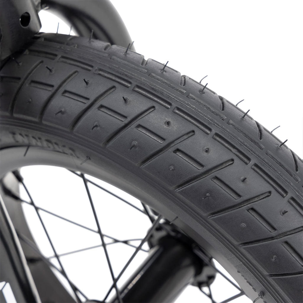 A close-up of a black bicycle tire featuring visible tread and spokes, echoing the robust design of the Kink Coast 12 Inch Balance Bike, showcases precision and durability.