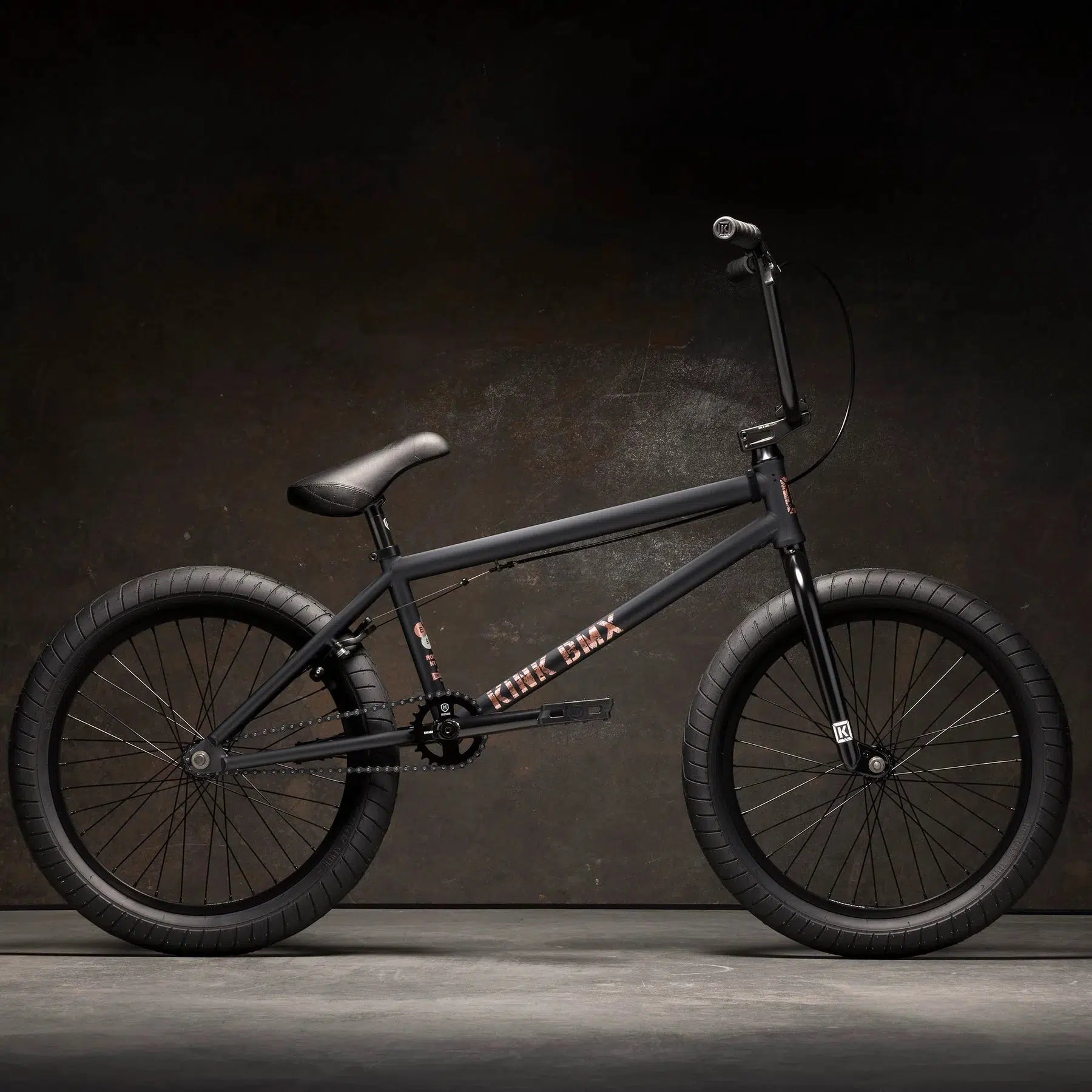 The stylish design of the Kink Gap 20 Inch Bike, featuring a semi-chromoly frame and robust tires, stands out vividly against a dark background.