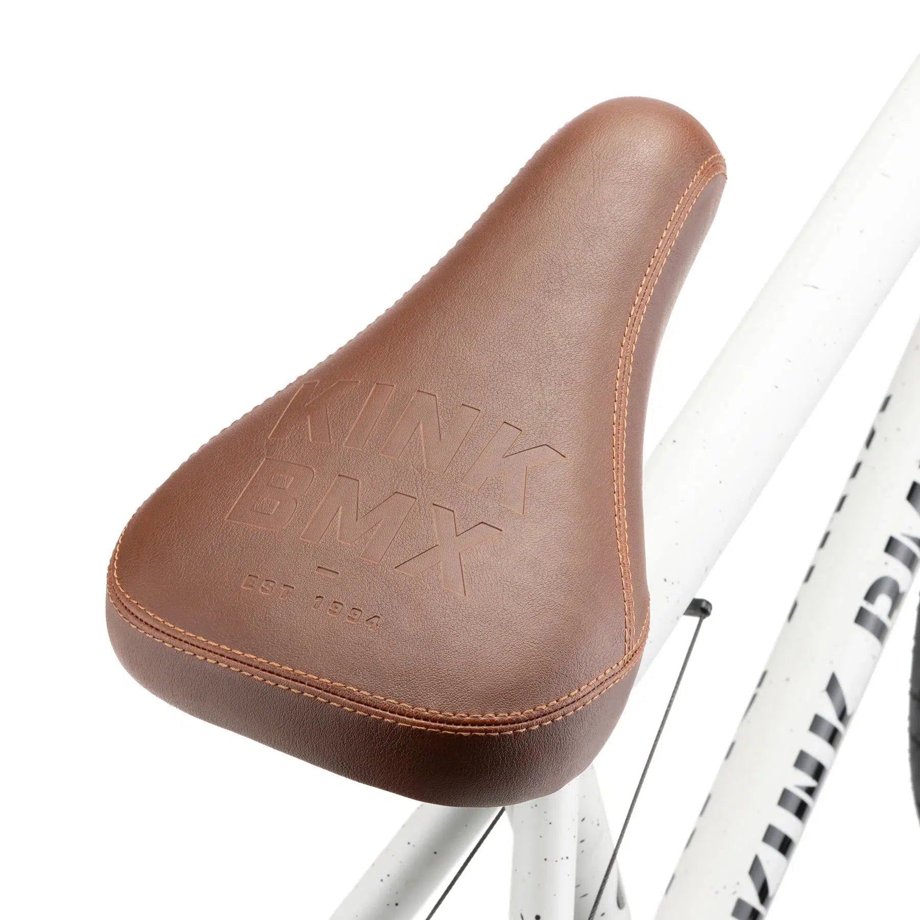 Close-up of a brown bike seat from the Kink Gap 20 Inch Bike, featuring embossed branding and stitching detail, mounted on its sleek semi-chromoly frame.