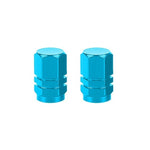 The Hexagon Valve Caps (Pair) in blue bring vibrant color to a white backdrop with their distinctive metal hexagonal design.