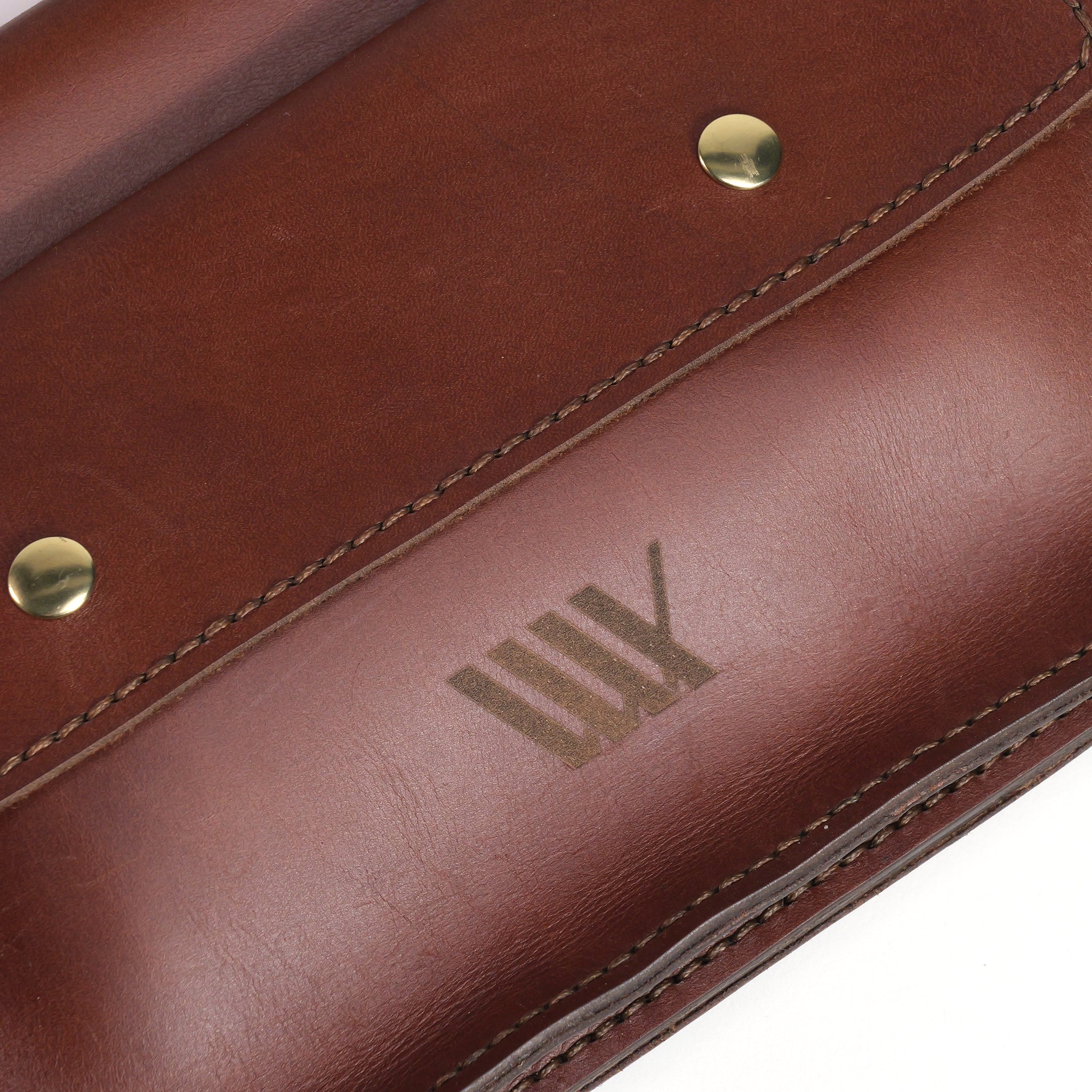Close-up of the LUXBMX Deluxe Leather Frame Bag, featuring full-grain leather, visible stitching, brass rivets, and a debossed geometric logo.