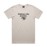 The LUXBMX Journey Tee - Bone is crafted from 100% combed cotton and features black "Embrace the journey." text above a minimalist mountain and winding road graphic. Enjoy comfort and style with this premium relaxed fit tee.