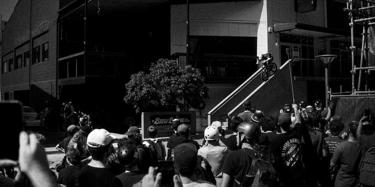 A rider on a handrail at a Brisbane street jam, with a crowd watching