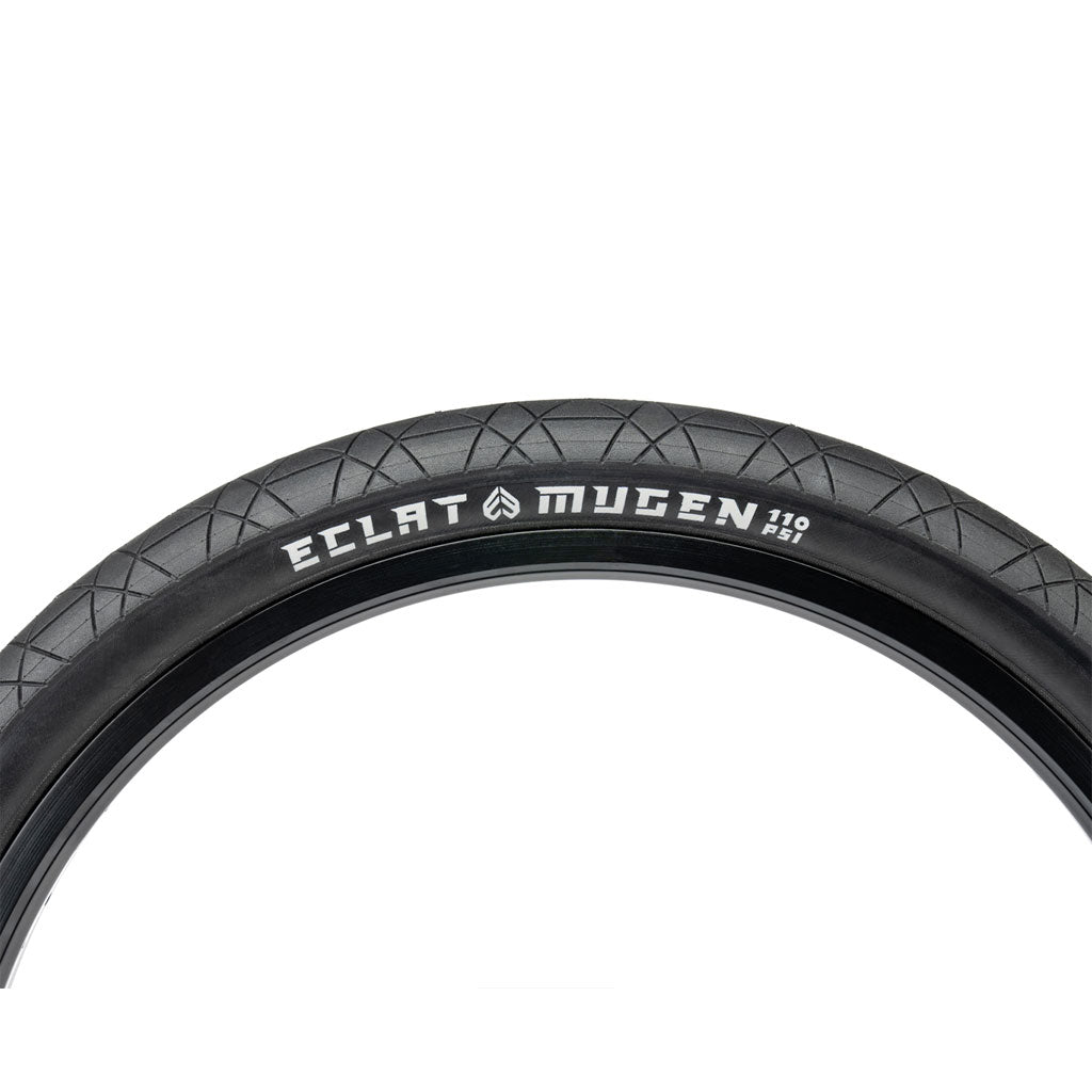 Close-up of the ECLAT Mugen Flatland Tyre, ideal for flatland riding, showcasing its unique tread pattern and prominent branding with size markings on the sidewall.