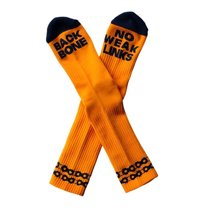 The Backbone No Weak Links Socks are bright orange with black toe caps, "BACK BONE" and "NO WEAK LINKS" text, plus a black chain pattern near the cuffs—ideal for showing strength while keeping your feet cool.