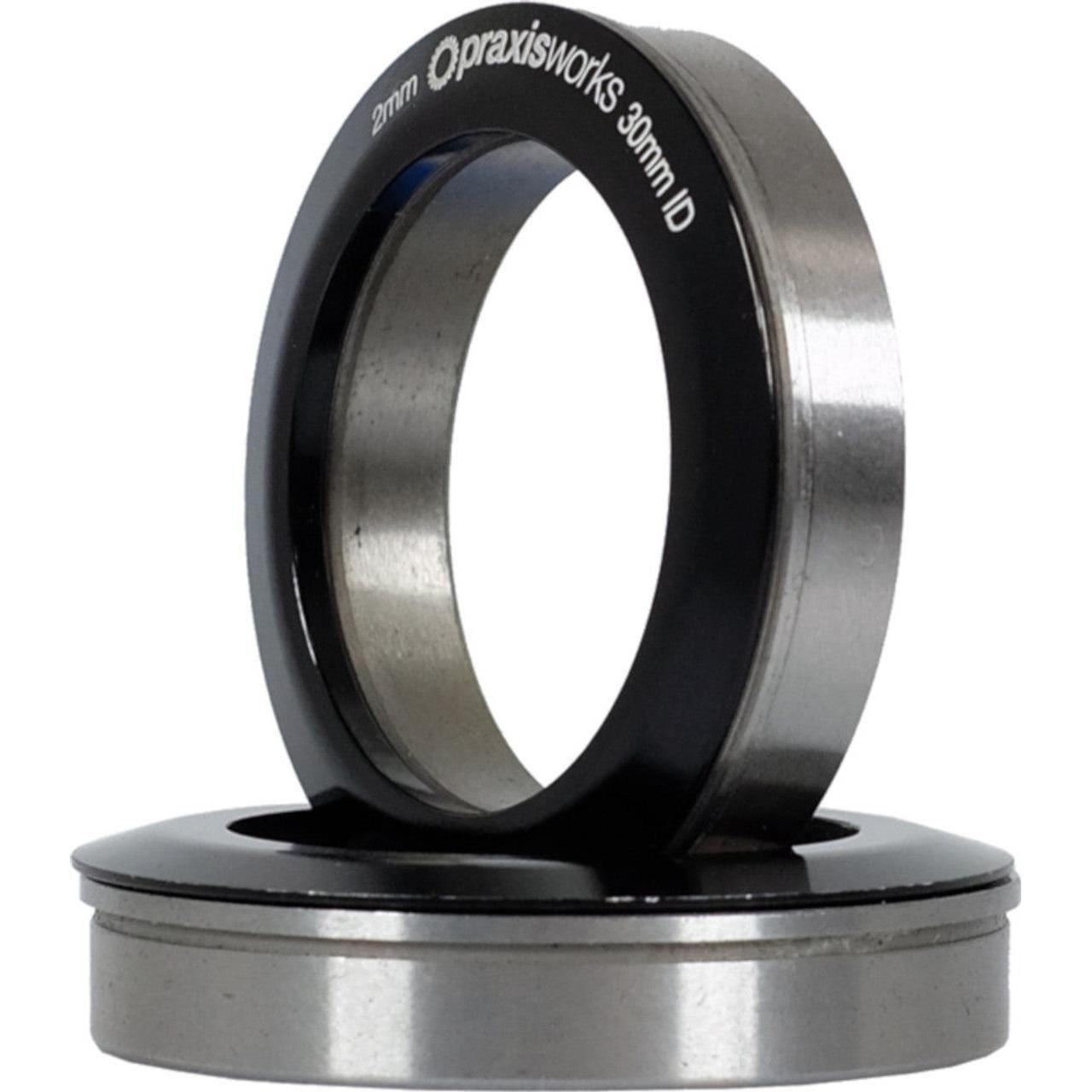 A black and stainless steel Praxis M30 THRU BB86/90/92 bearing ring on a white background.
