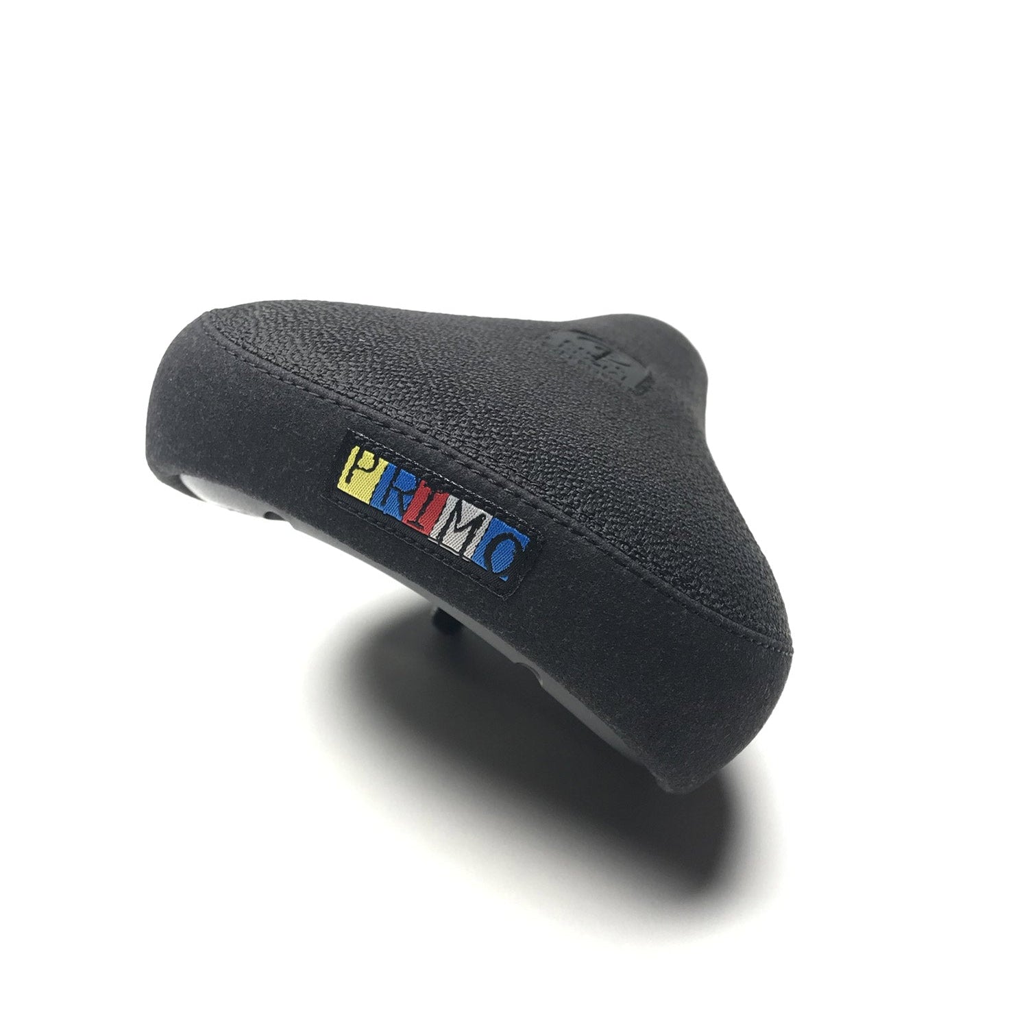 The Primo HD Pivotal Seat is a black bike seat with a textured surface and a small rectangular “PRIMO” logo in yellow, blue, and red on the back. Durable and designed for pivotal seat compatibility, it is shown against a white background.
