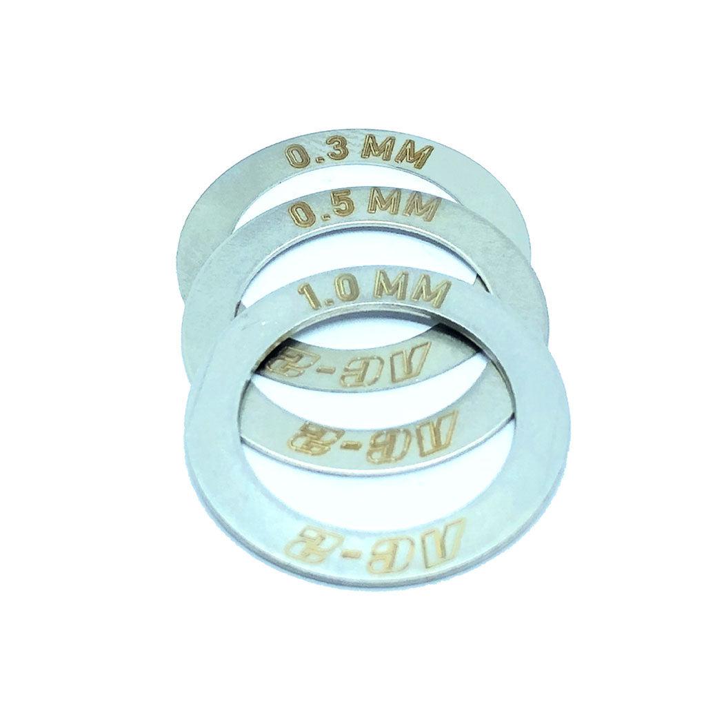 Four metal washers from the PROFILE AC2 HUB SHIM KIT, featuring engraved thickness measurements of 0.3 mm, 0.5 mm, 1.0 mm, and AC-8, are arranged in a slightly overlapping manner.