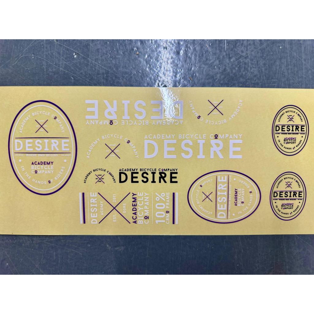 Academy Desire Sticker Pack: a 2016 purple and white sticker sheet featuring various circular and rectangular designs with the word “Desire” and brand text.