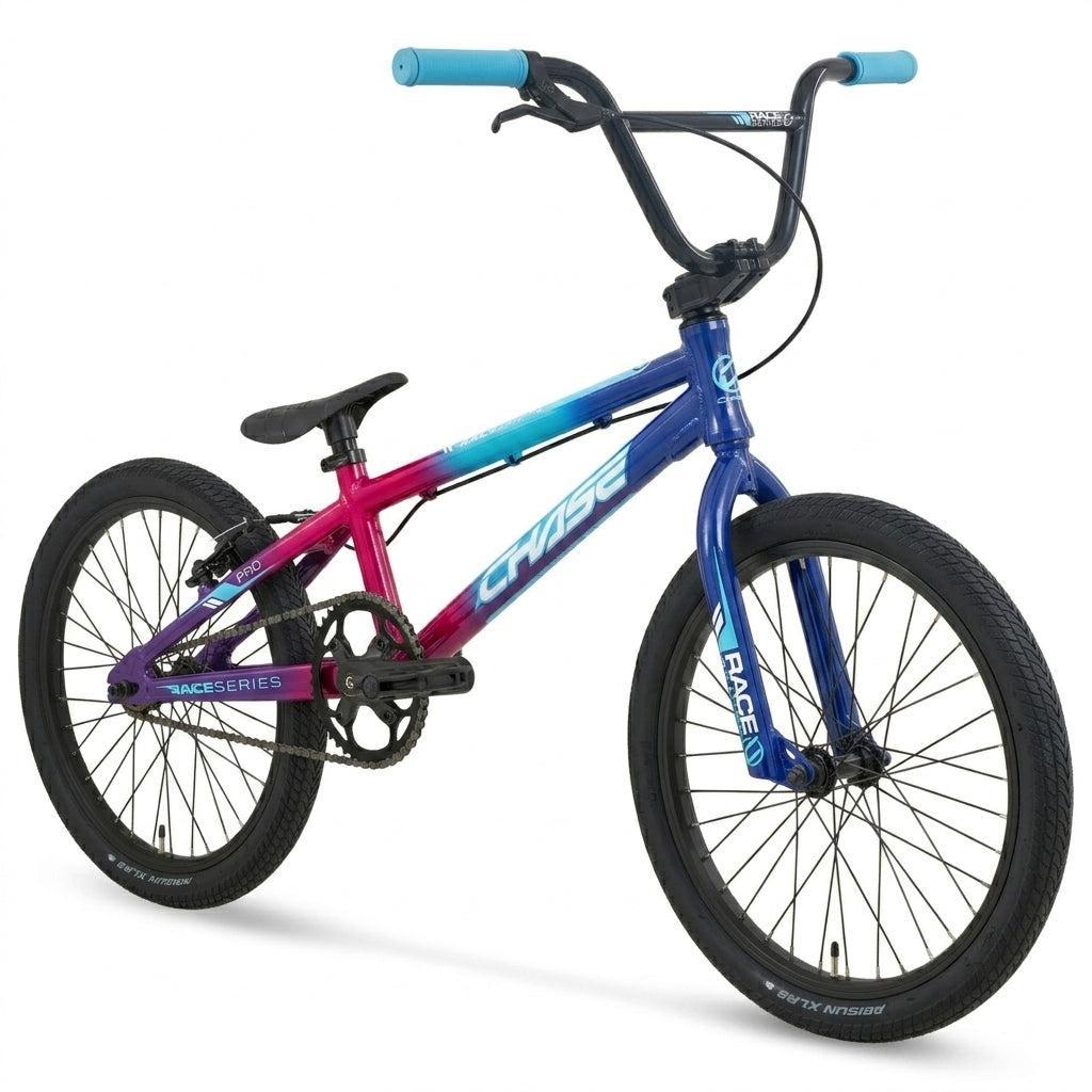A Chase Race Series Pro Race Bike (2027) featuring a gradient pink-to-blue frame, black wheels, blue handlebars, and a black seat is shown on a white background—making it an ideal entry-level race bike for new riders.