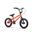 A small orange Radio Revo 14 Inch bike with black handlebars, black seat, and thick black wheels. The frame features the brand name, "REDLINE," making it an ideal first bike for young enthusiasts.