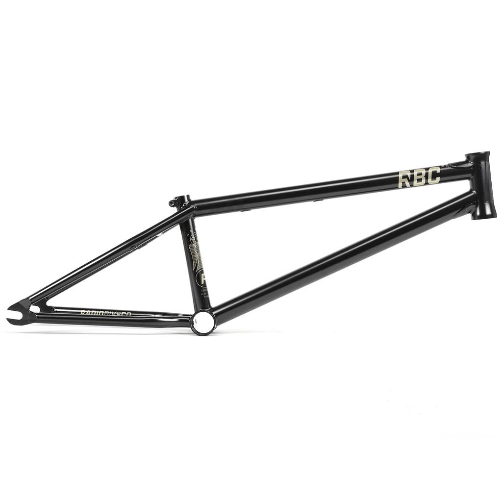 The Radio Saxon Frame is a black BMX frame with "RBC" on the top tube and minimal gold graphics, designed with technical skatepark geometry for a park-focused ride, shown on a white background.