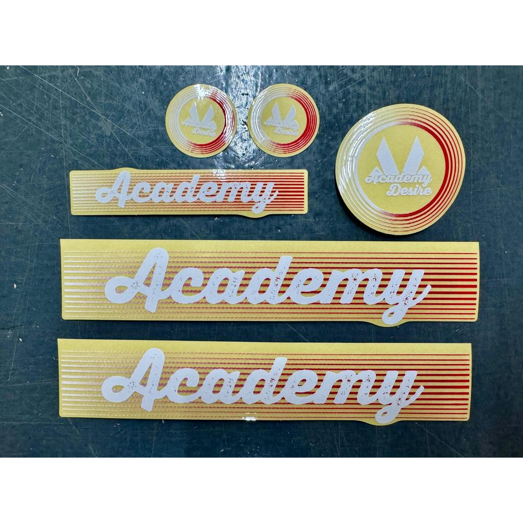 Academy Desire Sticker Pack for 2017 purple and grey models, featuring six stickers with red horizontal lines, white “Academy” script, two small circles, one large circle, and three rectangular strips.