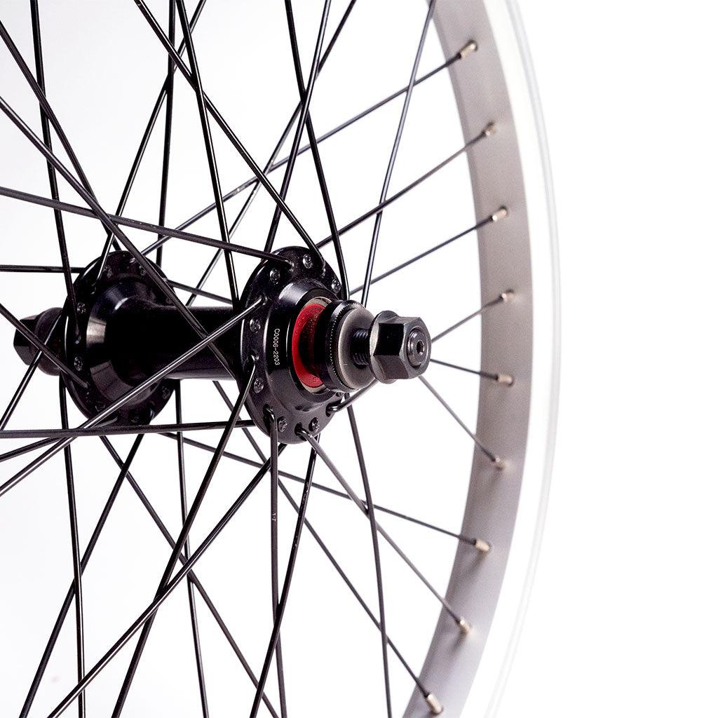 Close-up image of a Redline RL 20 B Complete wheelset featuring black spokes and a central hub with a hex nut, attached to a sturdy double wall rim.