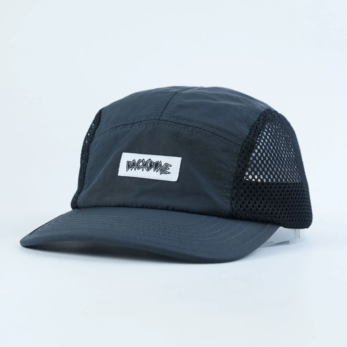 The Backbone Ride Club Hat features a black mesh-back design and a white rectangular patch on the front with stylized “BACKBONE” text, making it ideal for BMX fans and urban explorers.