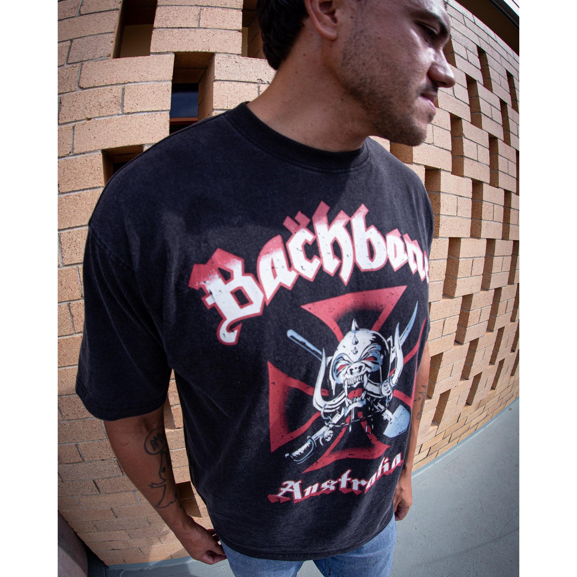 A person stands before a brick wall in the Backbone Road Crew Vintage T-Shirt—crafted from premium cotton, this tee features a graphic design with bold red lettering, showcasing classic Backbone BMX style.
