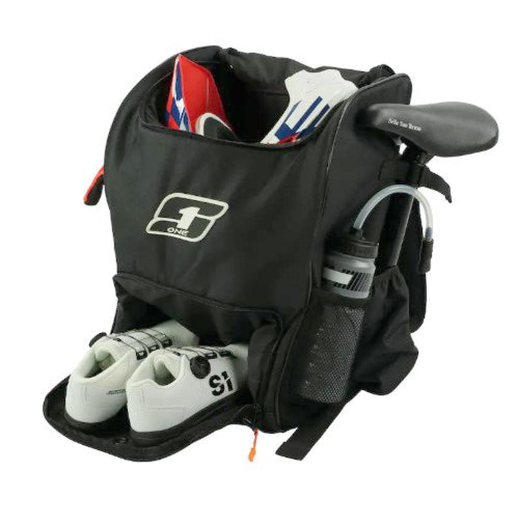 The S1 Helmet / Gear Backpack, in black, securely holds a pair of white cycling shoes, a helmet, a water bottle, and a bike saddle—each organized in its designated compartment.
