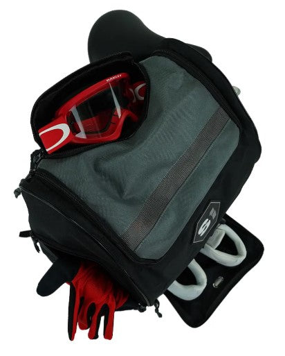 A black and gray S1 Helmet / Gear Backpack is open, showing red goggles, red gloves, and a white item inside. It has a zippered front pocket and a rectangular patch—ideal for organizing your gear essentials.