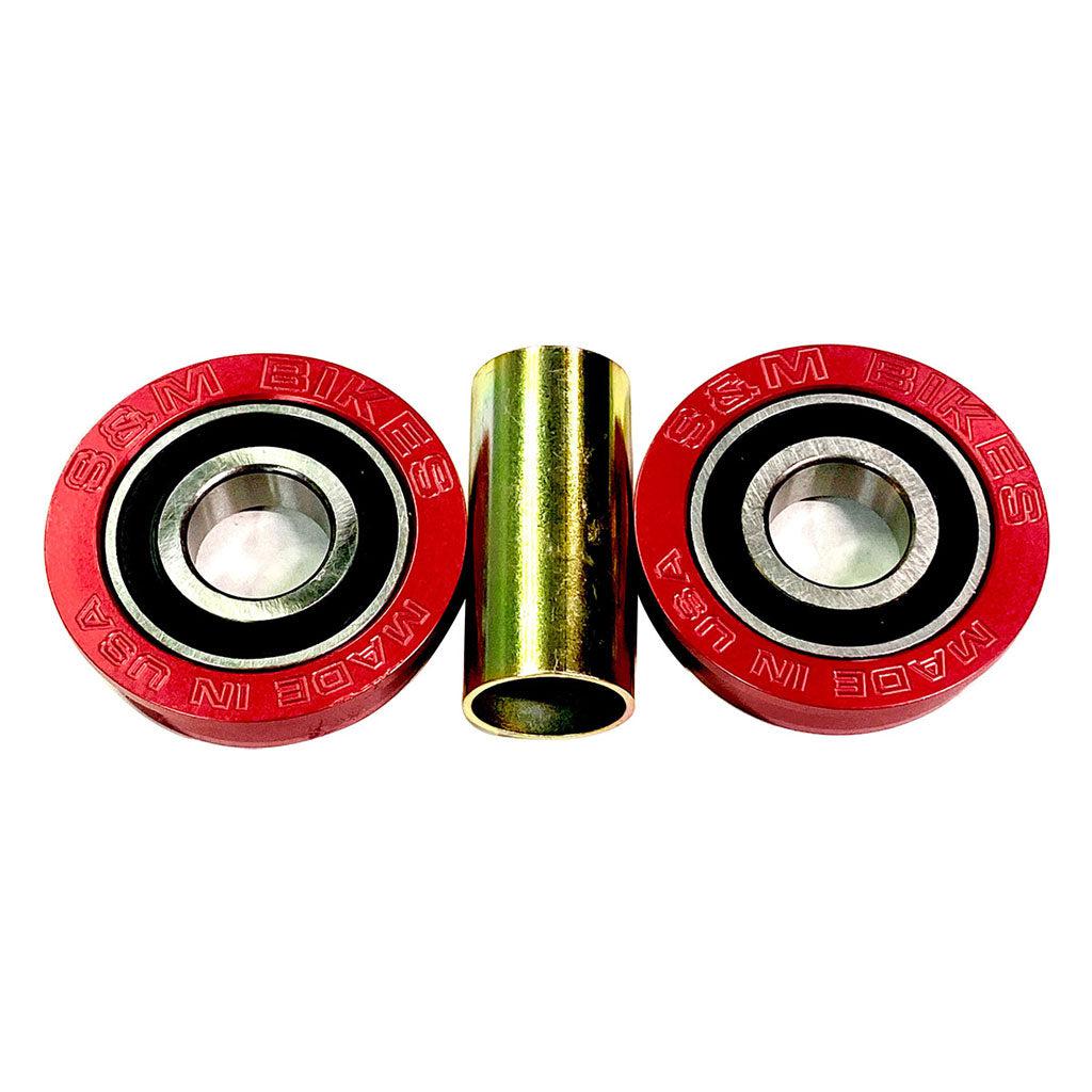 Two red circular bearings labeled "S&M USA Bottom Bracket Set / 19mm" flank a cylindrical metal spacer in the center, evoking the classic look of a retro rig against a white background.