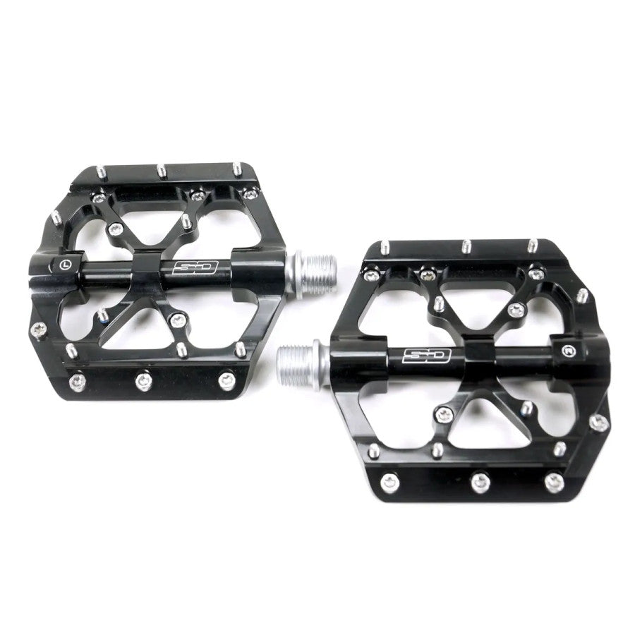 The SD CNC V3 Pro Pedal is a pair of black, flat BMX pedals with metal pins, silver axles, CNC machined bodies, and sealed bearings, shown side by side on a white background.