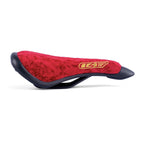The Shadow Penumbra Railed Seat, Trey Jones S11 Signature, showcases a red and black design with a textured surface and stitched logo. Ideal for Shadow rides, it's crafted for comfort with added durability and style through its railed construction.